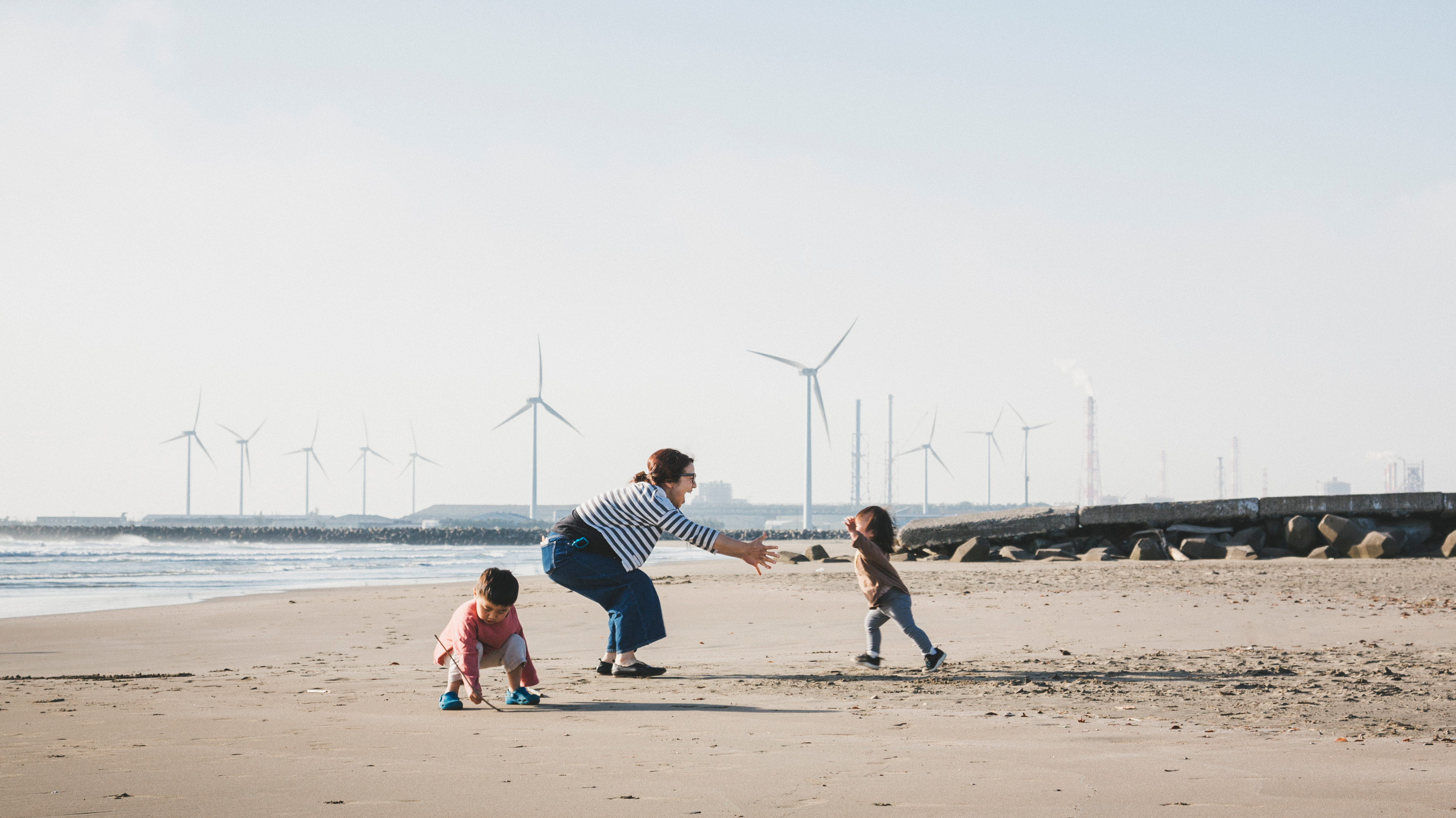 Family playing on beach with wind turbines in background